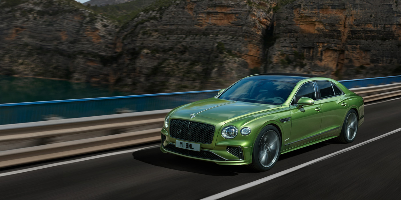 Feser-Graf Exclusive Cars GmbH | Bentley Nürnberg Bentley New Flying Spur Speed v8 hybrid sedan driving dynamically on a mountain road in Tourmaline Green paint