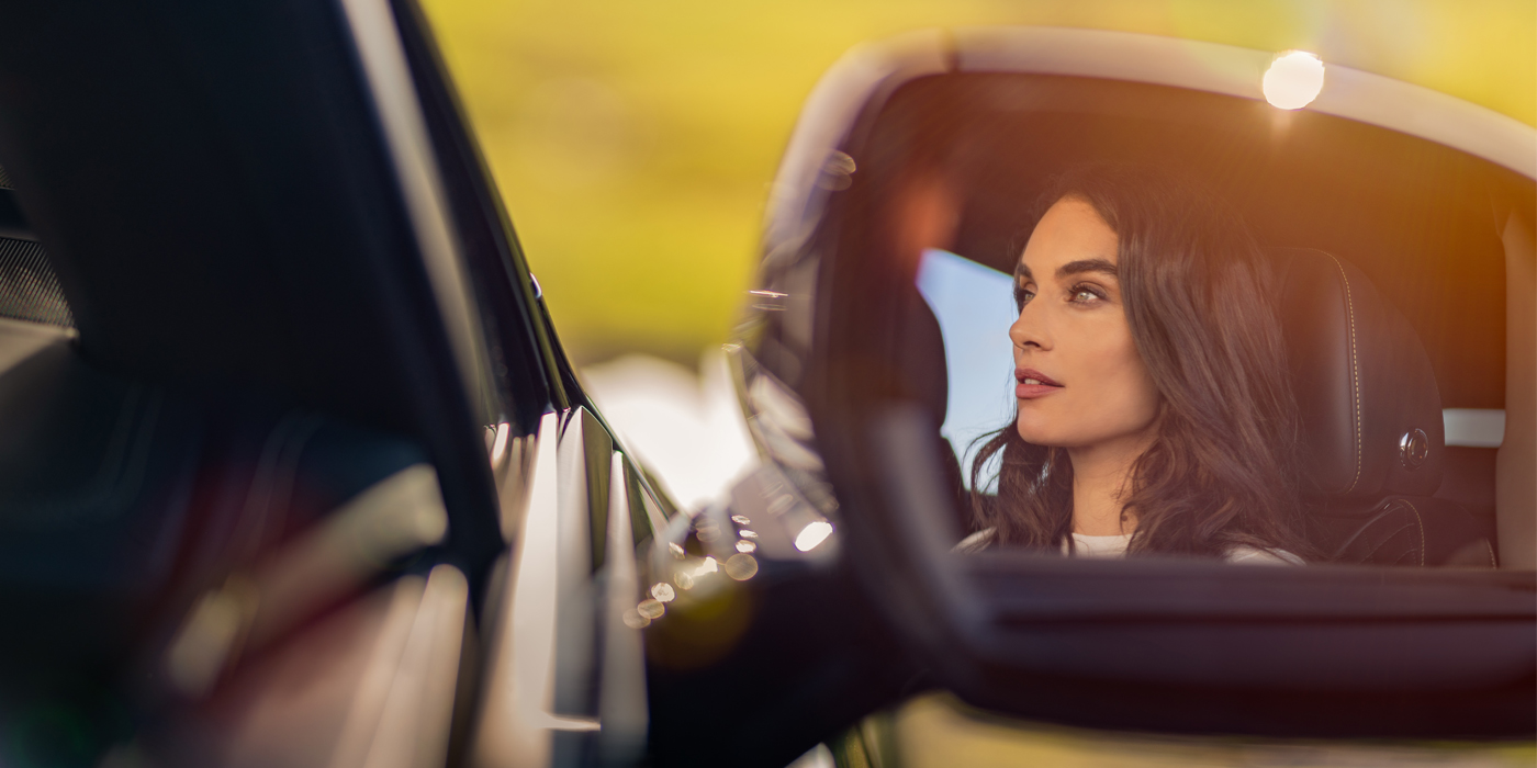Feser-Graf Exclusive Cars GmbH | Bentley Nürnberg profile of dark haired woman's face in mirror of Bentley car in sunlight