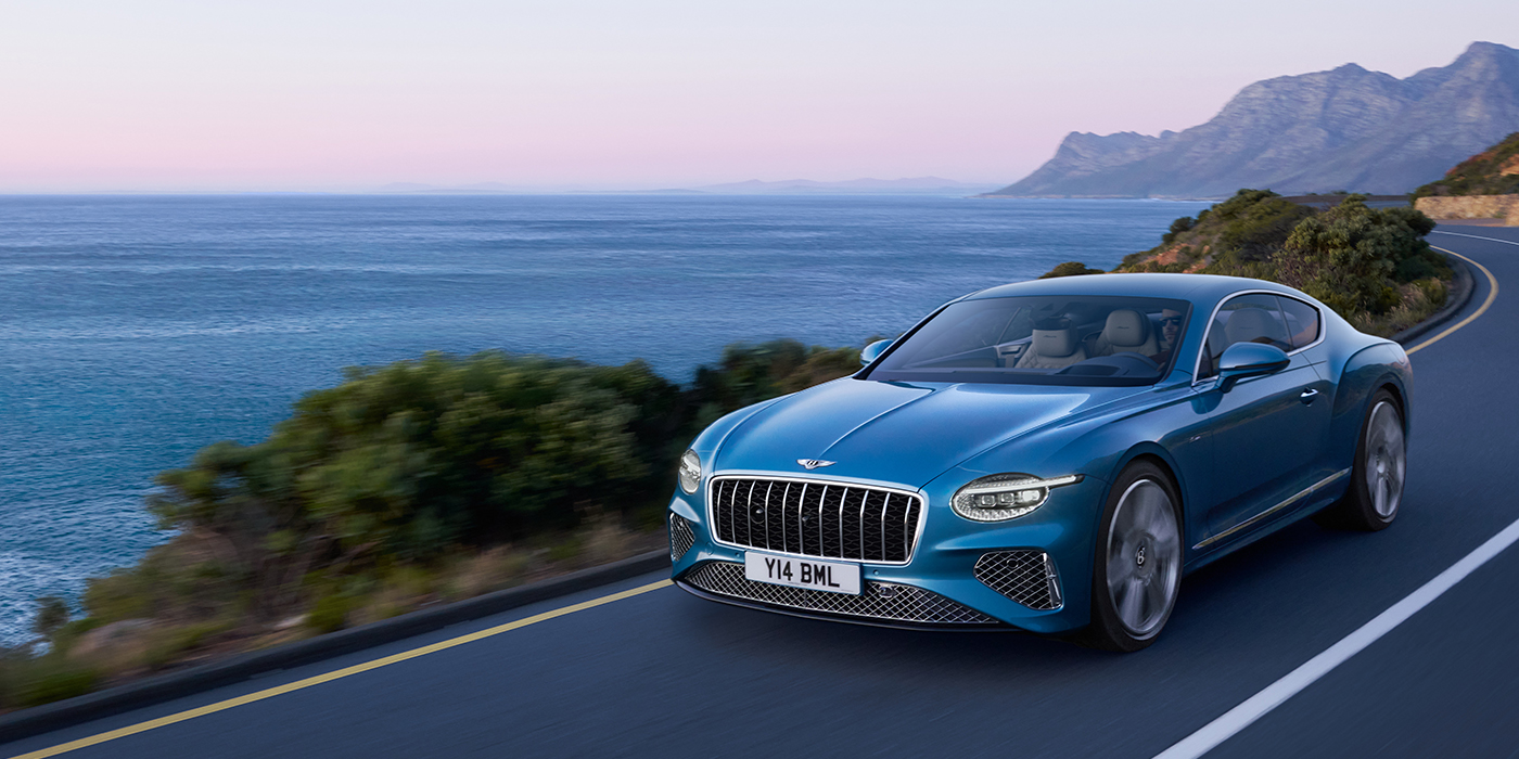 Feser-Graf Exclusive Cars GmbH | Bentley Nürnberg New Bentley Continental GT Azure coupe in Light Windsor blue paint with 22 inch Azure wheels and chrome grill, driving dynamically by the sea