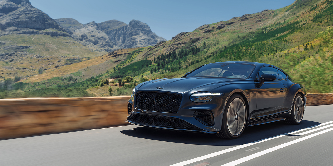 Feser-Graf Exclusive Cars GmbH | Bentley Nürnberg Bentley Continental GT coupe in Thunder paint and 22" ten swept spoke wheels front 3/4 driving on mountain road