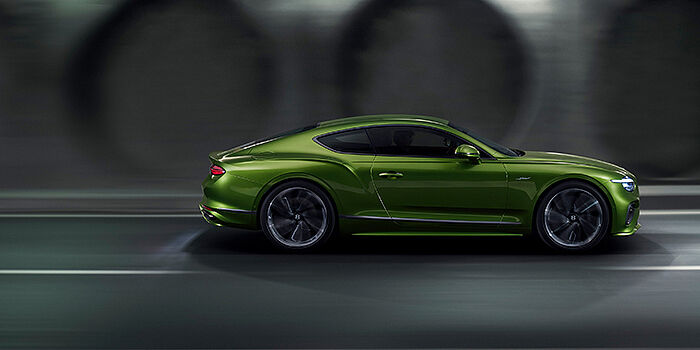  Feser-Graf Exclusive Cars GmbH | Bentley Nürnberg Bentley Continental GT coupe in Tourmaline Green paint driving in profile on a dark road
