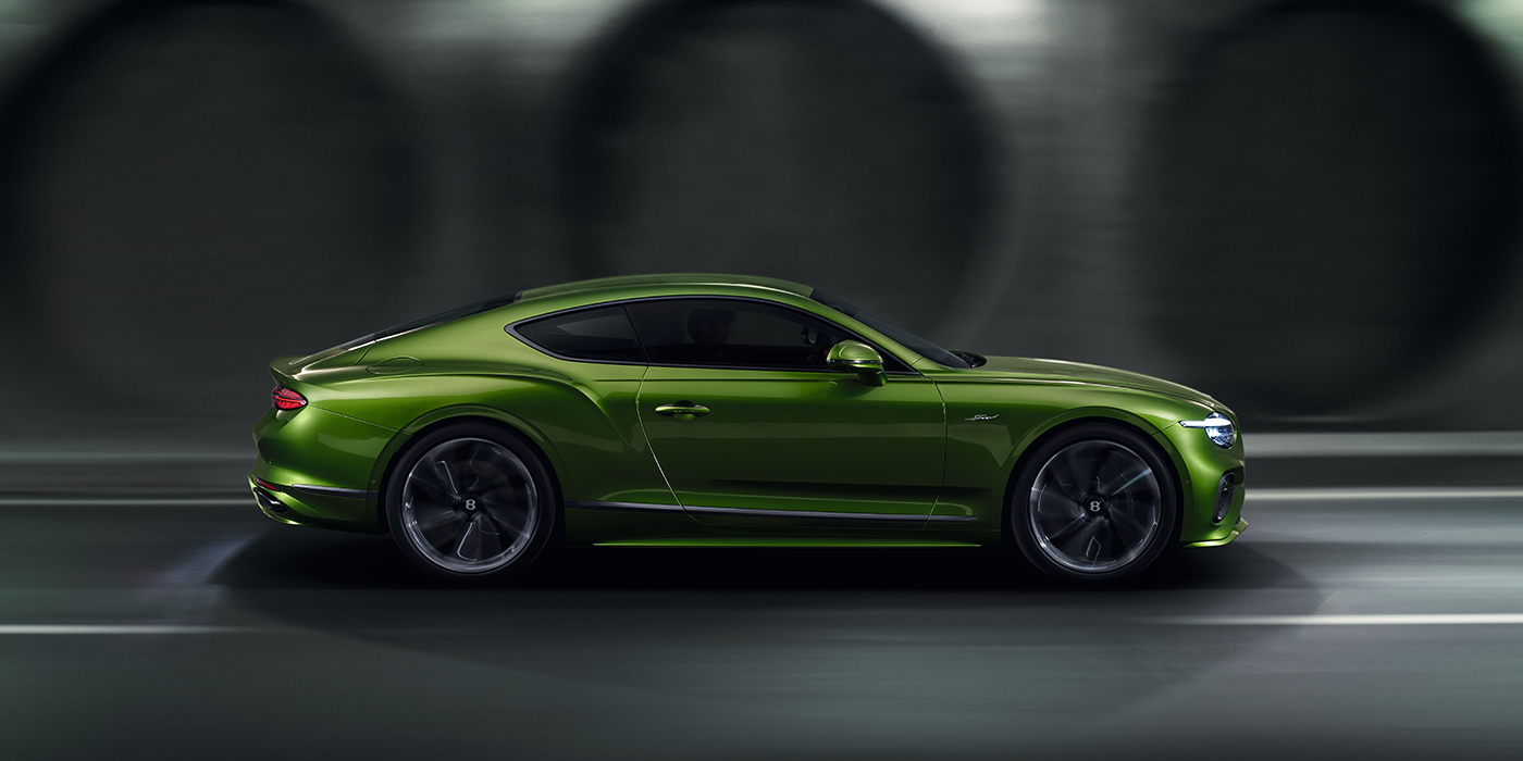 Feser-Graf Exclusive Cars GmbH | Bentley Nürnberg Bentley Continental GT coupe in Tourmaline Green paint driving in profile on a dark road